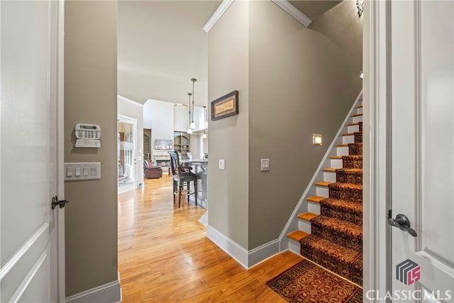 staircase featuring a high ceiling, ornamental molding, and hardwood / wood-style floors