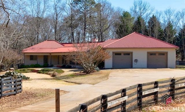 view of front of house featuring stucco siding, an attached garage, fence, driveway, and a tiled roof