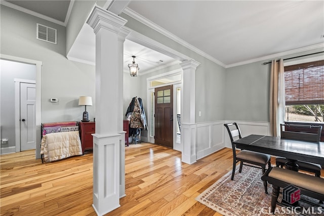 dining area with crown molding, decorative columns, and light wood-type flooring