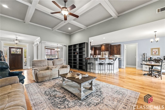 living room featuring ornate columns, coffered ceiling, light hardwood / wood-style floors, and beamed ceiling