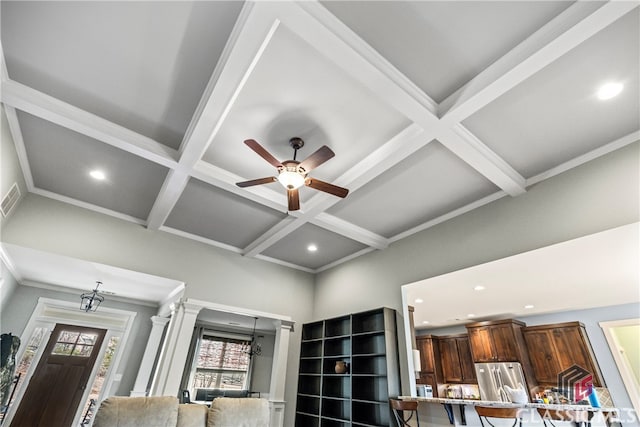 details featuring crown molding, stainless steel refrigerator, beam ceiling, coffered ceiling, and ornate columns