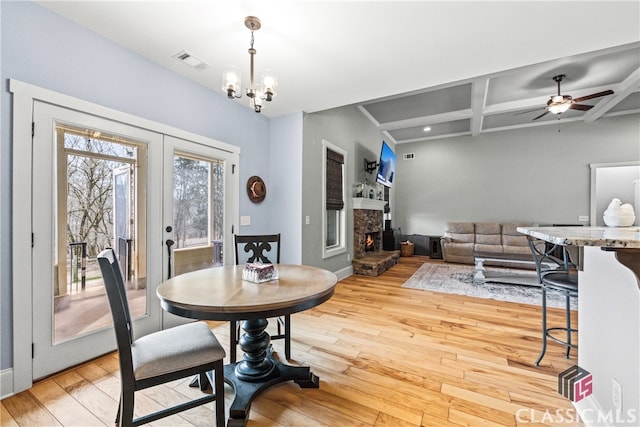 dining space featuring beamed ceiling, coffered ceiling, hardwood / wood-style floors, and a fireplace