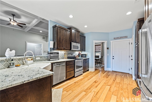 kitchen with appliances with stainless steel finishes, tasteful backsplash, sink, coffered ceiling, and light stone countertops