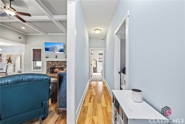 corridor featuring coffered ceiling, beam ceiling, and light hardwood / wood-style flooring