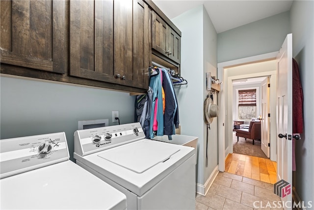 clothes washing area featuring cabinets, washer and clothes dryer, and light tile patterned floors