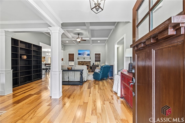 interior space featuring ceiling fan with notable chandelier, decorative columns, coffered ceiling, light hardwood / wood-style floors, and beam ceiling