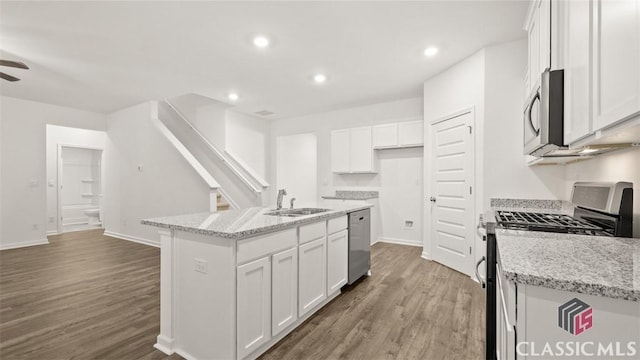 kitchen featuring stainless steel appliances, an island with sink, sink, and white cabinets