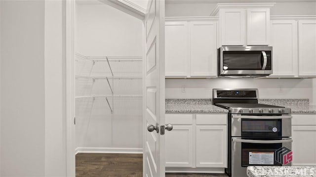 kitchen featuring white cabinetry, light stone counters, dark hardwood / wood-style floors, and appliances with stainless steel finishes