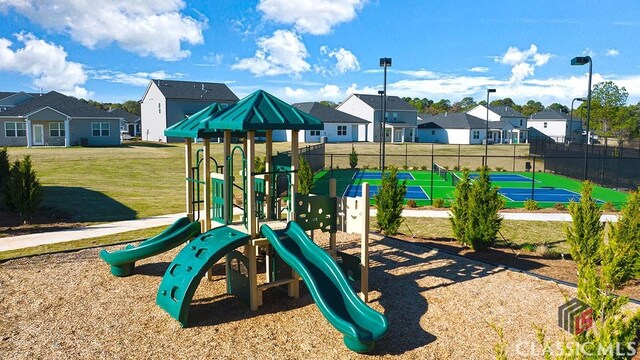 view of jungle gym featuring tennis court and a lawn