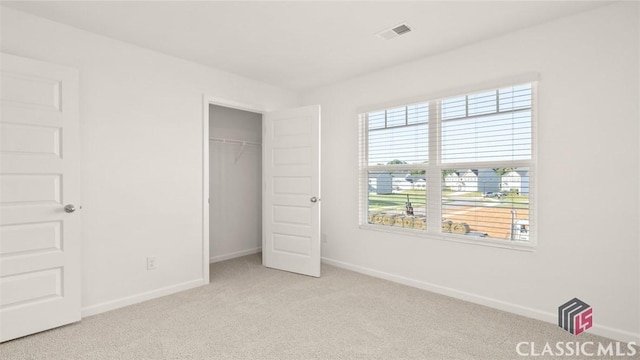 unfurnished bedroom with light colored carpet and a closet