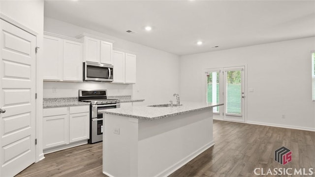 kitchen with white cabinetry, appliances with stainless steel finishes, light stone countertops, and a center island with sink