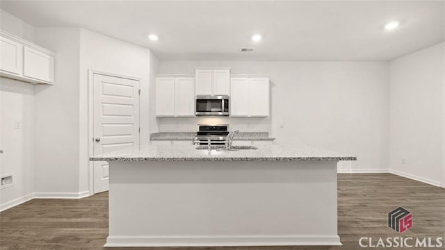 kitchen with stainless steel appliances, an island with sink, sink, and white cabinets