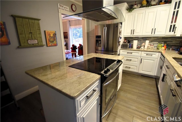 kitchen featuring appliances with stainless steel finishes, white cabinets, island exhaust hood, light stone countertops, and light hardwood / wood-style flooring