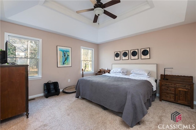 bedroom with ceiling fan, light colored carpet, and a raised ceiling