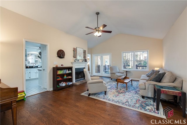 living room featuring dark wood-type flooring, ceiling fan, and vaulted ceiling