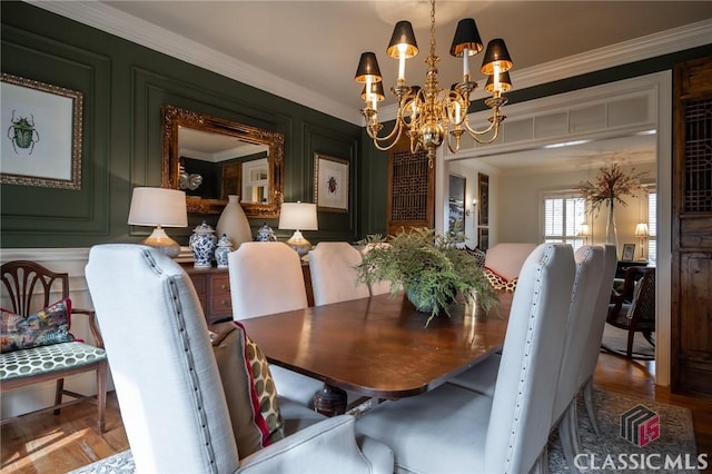 dining area with ornamental molding, a chandelier, and hardwood / wood-style floors