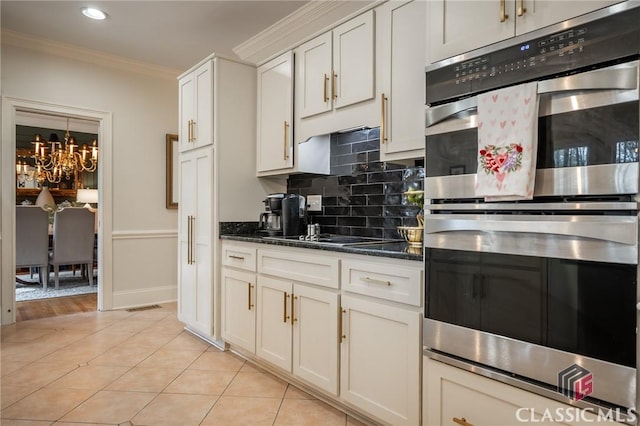 kitchen with crown molding, dark stone countertops, double oven, white cabinetry, and decorative backsplash