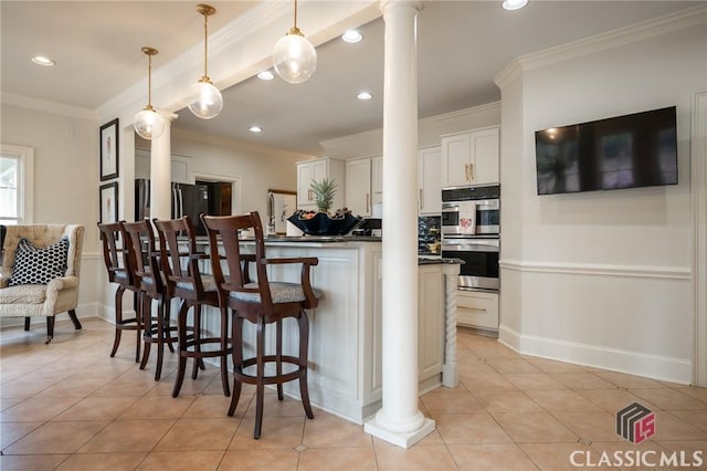 kitchen with pendant lighting, appliances with stainless steel finishes, decorative columns, white cabinets, and light tile patterned flooring