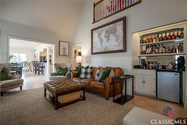 living room featuring a notable chandelier, bar area, high vaulted ceiling, and light tile patterned floors