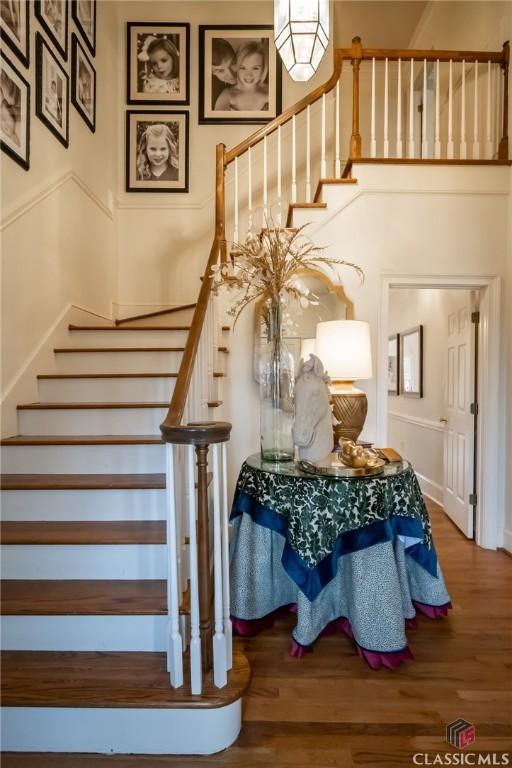 stairs with hardwood / wood-style floors and a high ceiling