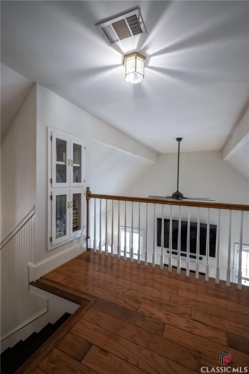 hall with wood-type flooring and vaulted ceiling