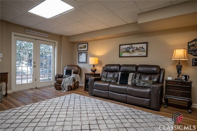 living room with a drop ceiling, hardwood / wood-style flooring, and french doors