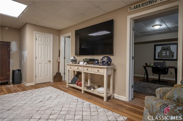 living room with a paneled ceiling and wood-type flooring