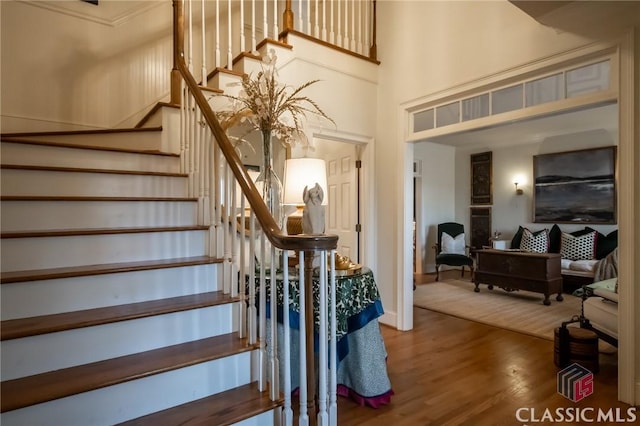 staircase with hardwood / wood-style flooring and a towering ceiling