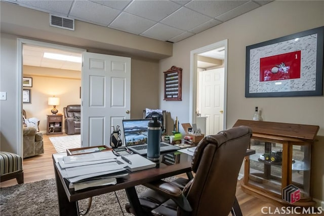 office with light hardwood / wood-style flooring and a paneled ceiling