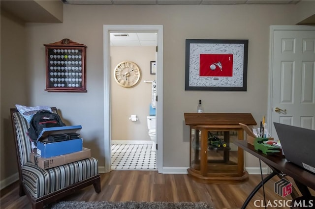 living area featuring wood-type flooring and a paneled ceiling