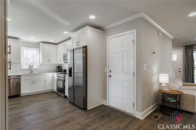 kitchen with dark hardwood / wood-style flooring, crown molding, white cabinets, and appliances with stainless steel finishes