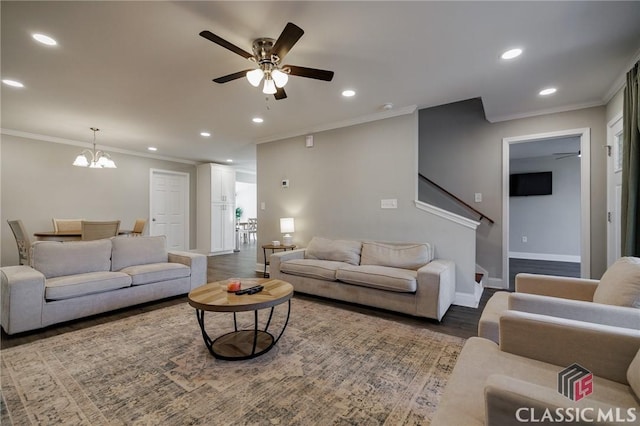 living room with hardwood / wood-style flooring, ornamental molding, and ceiling fan with notable chandelier