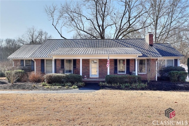 ranch-style house featuring covered porch and a front lawn