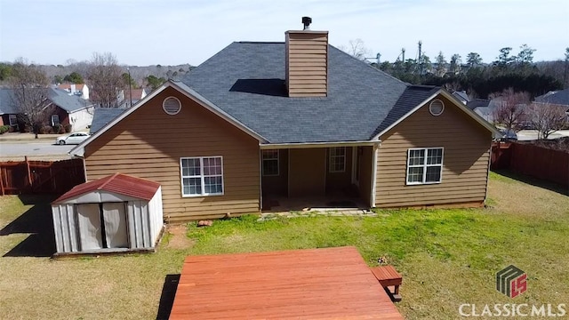 back of house with a deck, a lawn, and a storage shed