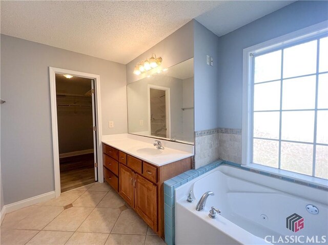 bathroom with ceiling fan, tile patterned flooring, vanity, a textured ceiling, and a bathing tub