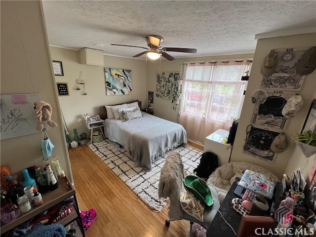 bedroom with a textured ceiling, wood-type flooring, and ceiling fan