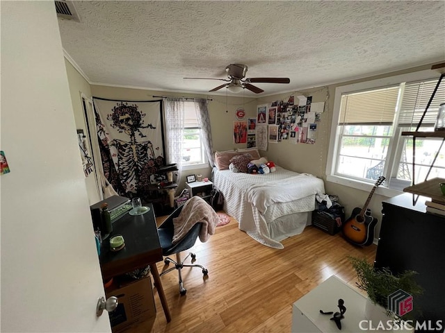 bedroom with crown molding, ceiling fan, light hardwood / wood-style flooring, and a textured ceiling