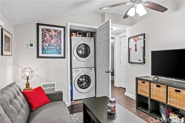 clothes washing area featuring dark wood-type flooring, ceiling fan, and stacked washing maching and dryer