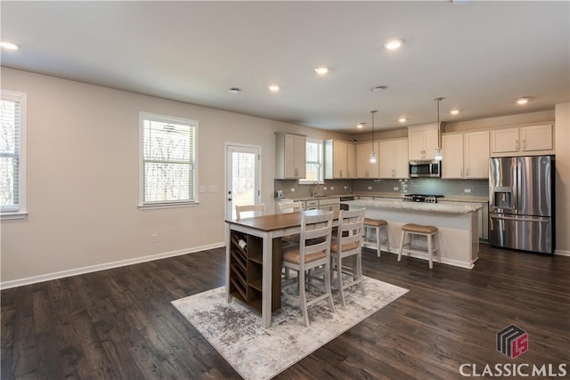 kitchen with a kitchen island, appliances with stainless steel finishes, pendant lighting, white cabinets, and decorative backsplash