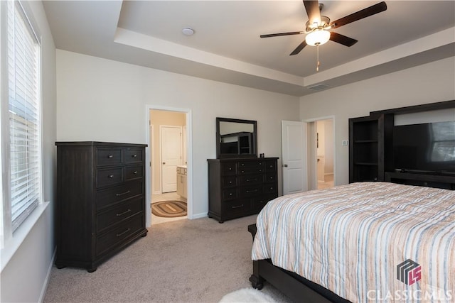 carpeted bedroom with ceiling fan, ensuite bathroom, and a tray ceiling