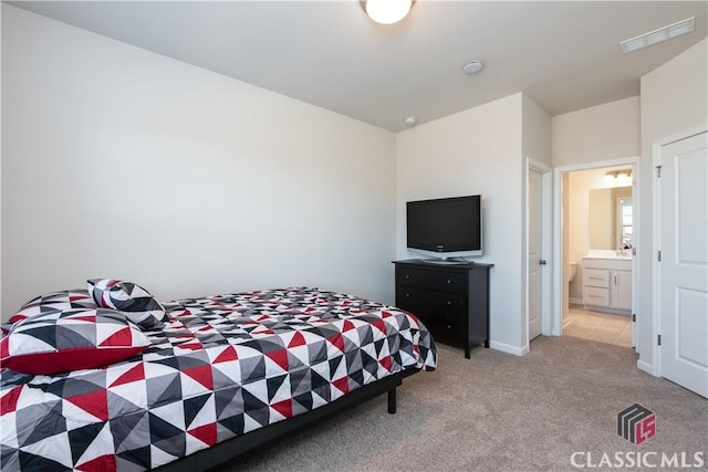 bedroom featuring ensuite bathroom and light carpet