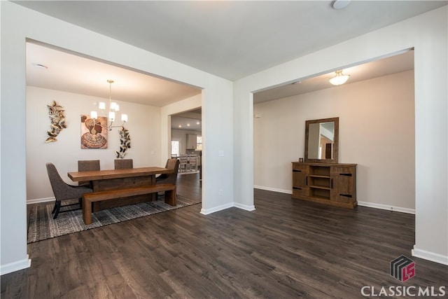 dining space featuring dark wood-type flooring and an inviting chandelier