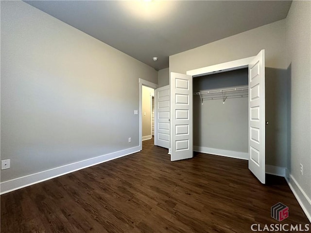 unfurnished bedroom with dark hardwood / wood-style floors and a closet