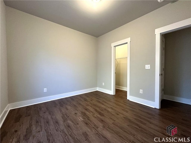 unfurnished bedroom with a walk in closet, dark hardwood / wood-style floors, and a closet