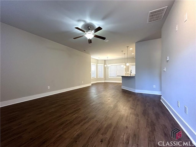 unfurnished living room featuring sink, dark wood-type flooring, and ceiling fan with notable chandelier