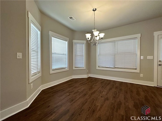 unfurnished dining area featuring dark hardwood / wood-style floors and a chandelier