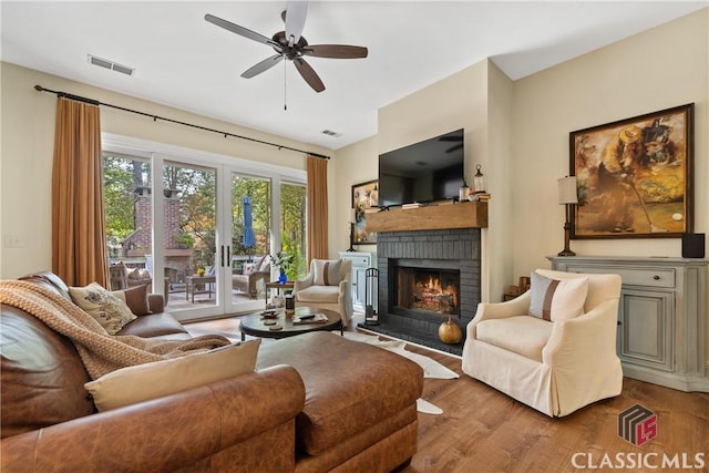 living room featuring ceiling fan, wood-type flooring, and a fireplace