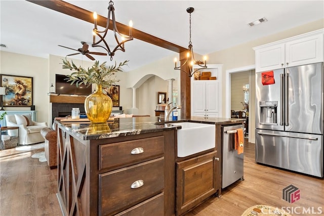 kitchen with appliances with stainless steel finishes, white cabinetry, sink, a kitchen island with sink, and light hardwood / wood-style flooring