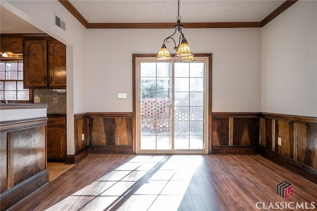 unfurnished dining area featuring crown molding, a chandelier, and light hardwood / wood-style flooring