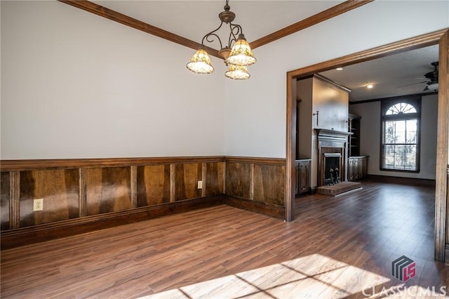 spare room featuring hardwood / wood-style flooring, ornamental molding, and ceiling fan with notable chandelier